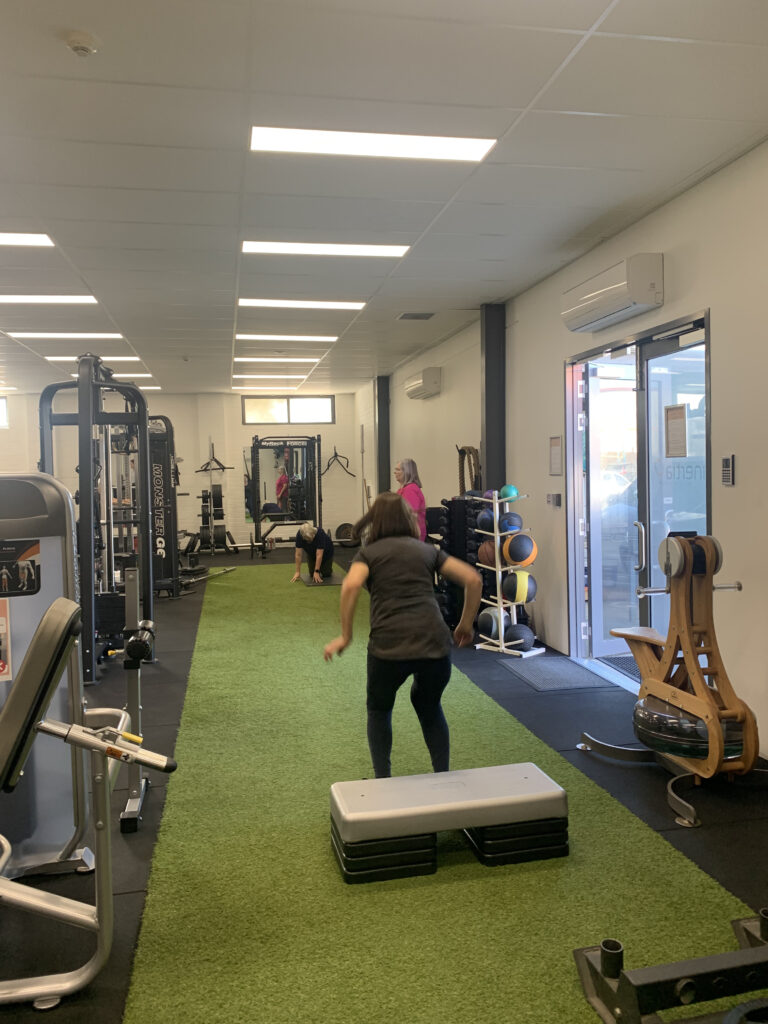 A group of women exercising together in a gym under the supervision of an exercise physiologist