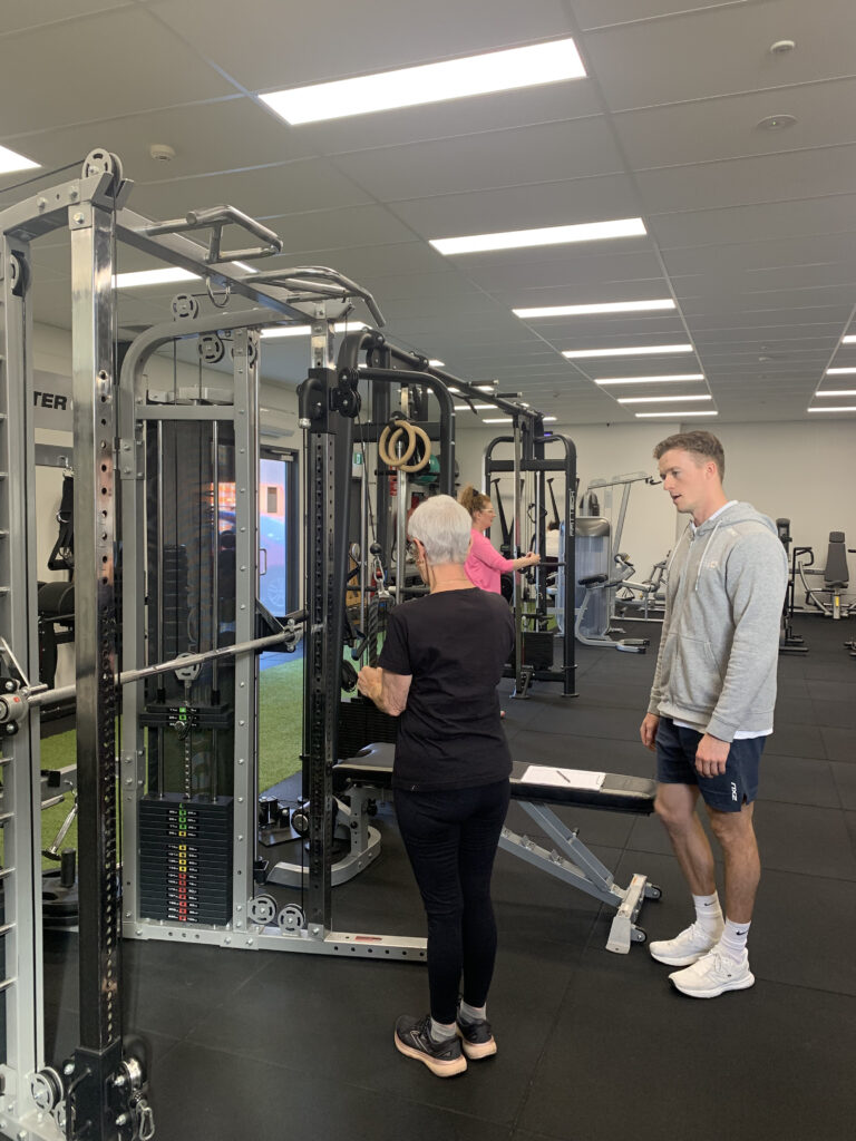 A person lifting weights with focus and determination under the guidance of an exercise physiologist
