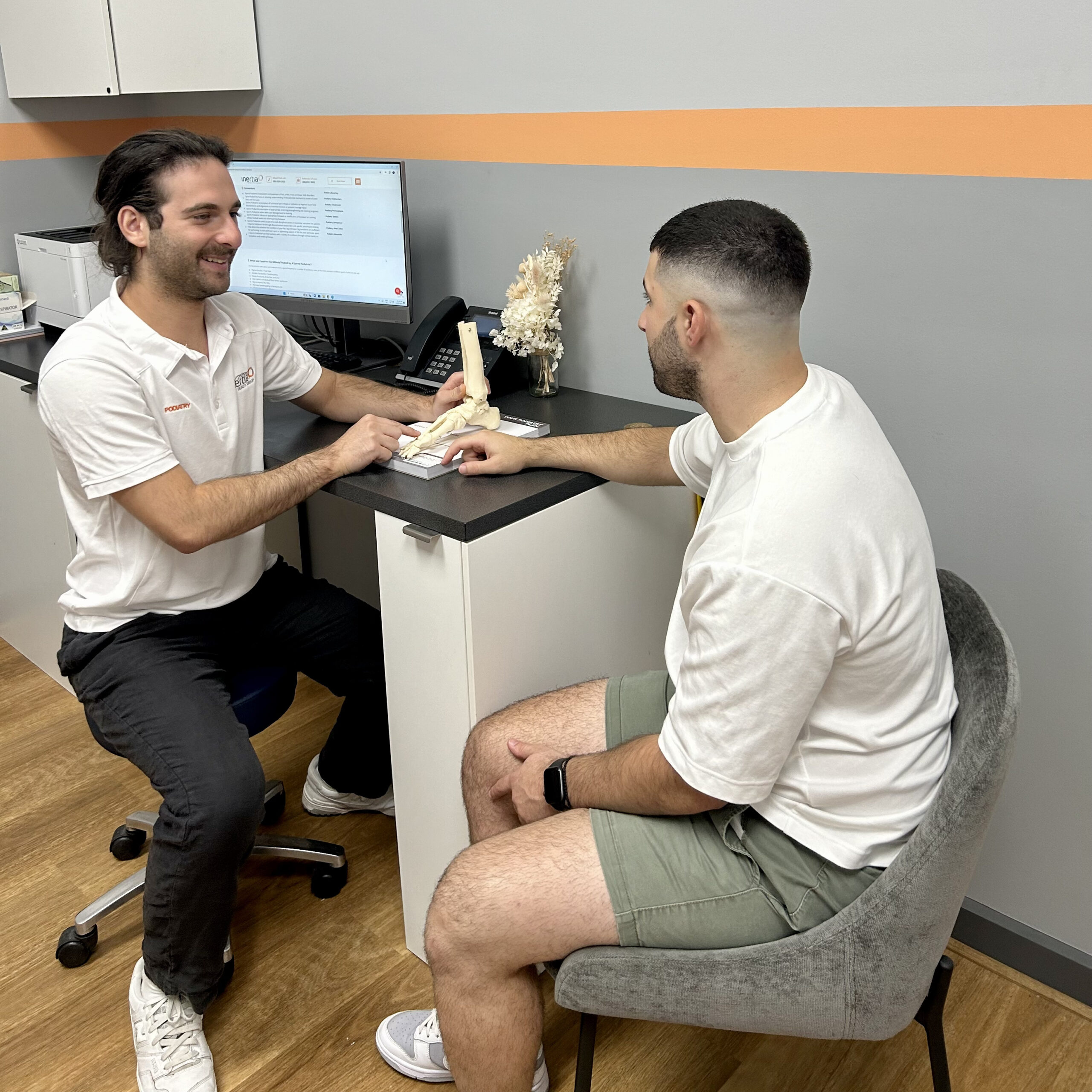 A podiatrist discusses foot health with his patient during a consultation, using visual aids.