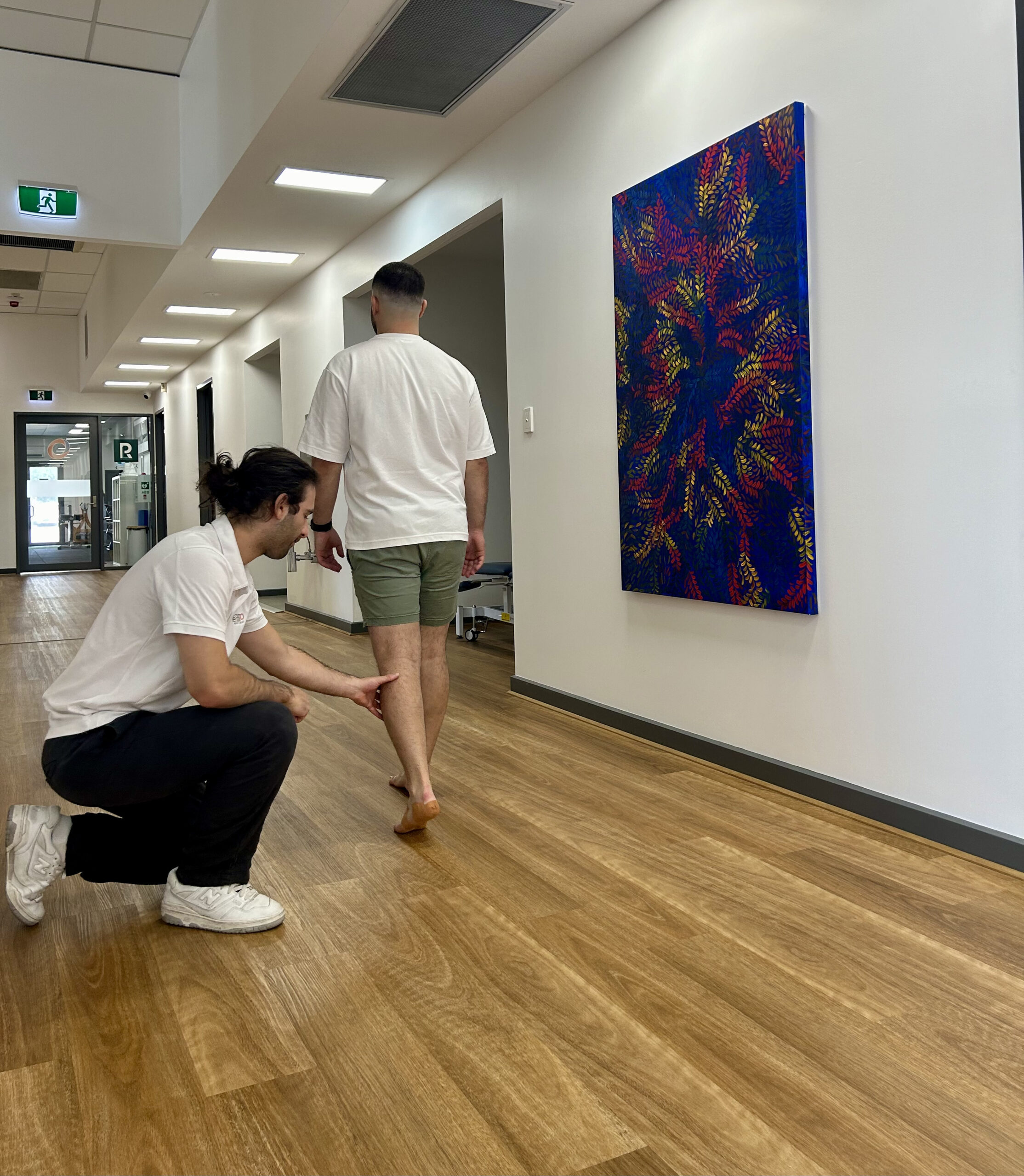 A podiatrist examining a patient's leg in a clinical setting at Inertia Health Group's Port Adelaide clinic